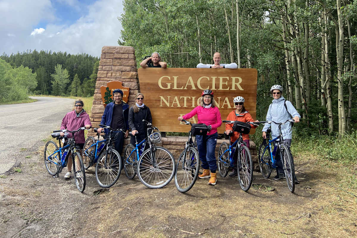Guests posing with their bikes in front of the Glacier National Park sign